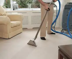 Carpet cleaning professional removing dirt and stains with a hot-water extraction tool in a home, Fresno, CA.