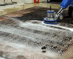 Professional rug cleaning with a rotary floor machine and shampoo foam, deep-cleaning an area rug, in Fresno, CA.